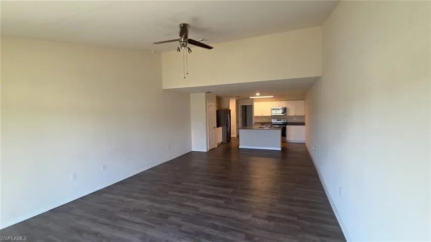 Open-concept living area featuring wood-finish flooring, vaulted ceilings, and a ceiling fan