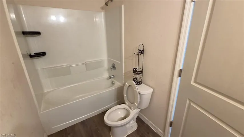 Tub/shower combination with integrated shelving, chrome fixtures, and wood-finish flooring