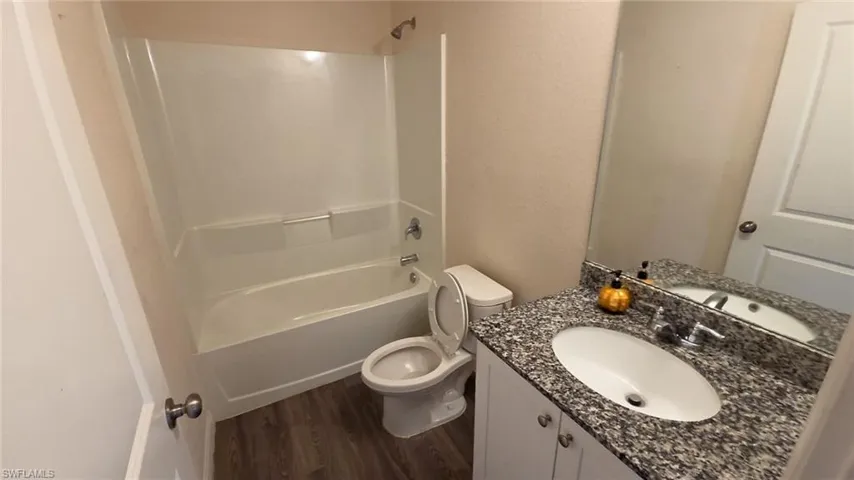 Bathroom featuring a single vanity with a granite-style countertop, undermount sink, and chrome faucet