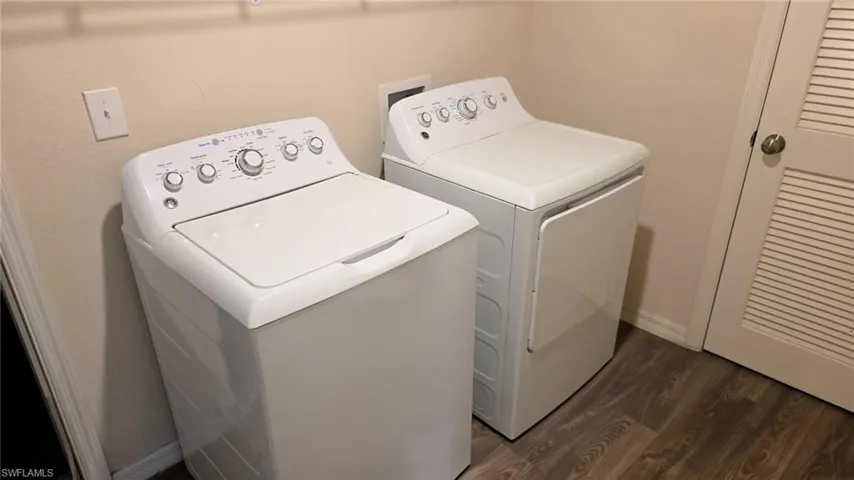 Dedicated laundry area featuring wood-finish flooring and a louvered bi-fold door