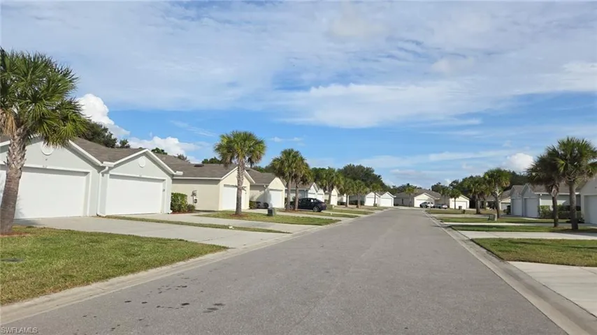 Residential street featuring single-story homes with stucco exteriors and attached garages