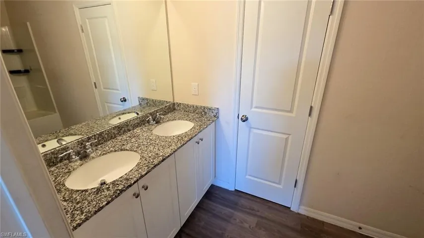 Double vanity featuring a granite-finish countertop, two undermount sinks, and chrome faucets