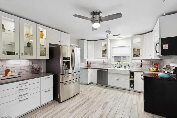 Kitchen with ceiling fan, stainless steel appliances, backsplash, sink, and white cabinets