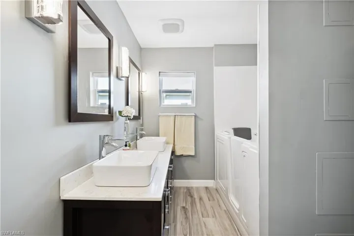 Bathroom with wood-type flooring, oversized vanity, and double sink