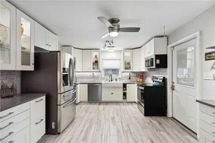 Kitchen featuring white cabinets, appliances with stainless steel finishes, and backsplash