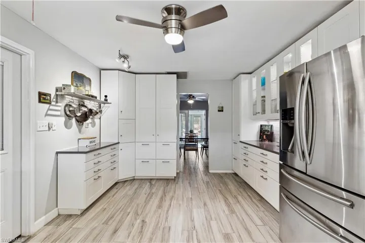 Kitchen featuring white cabinets, ceiling fan, stainless steel fridge, and light hardwood / wood-style floors
