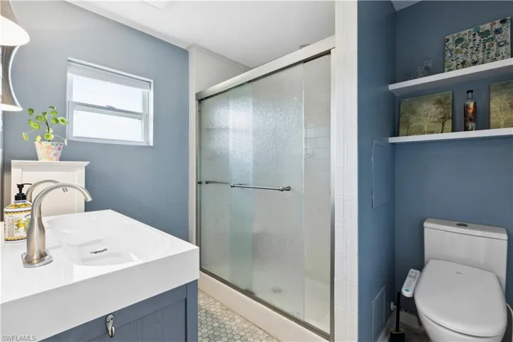 Bathroom featuring a shower with door, tile flooring, toilet, and vanity