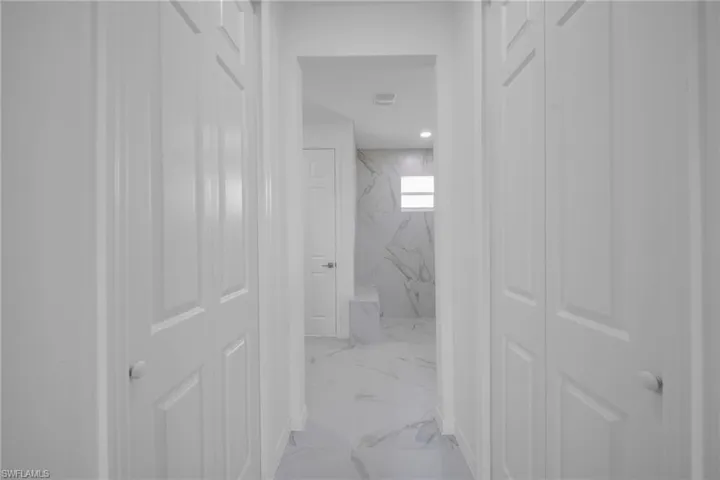 Hallway featuring crisp white paneled doors and uniform white trim