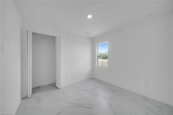 GUEST BEDROOM 1Bright room with white walls, recessed lighting, and a single window