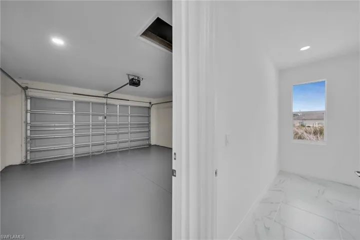 Attached garage with a roll-up door, overhead opener, and recessed lighting