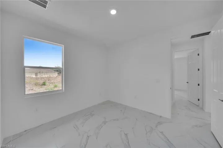 GUEST BEDROOM 2 Room with a single window offering exterior views, featuring white walls, large format tile flooring, a recessed ceiling light, and a white paneled door
