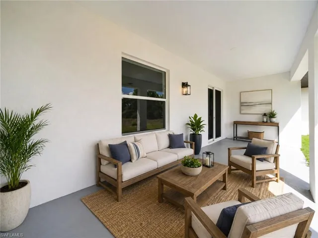 Covered outdoor patio featuring a neutral color palette, a rectangular window, and a wall-mounted exterior light fixture