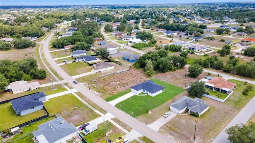 Expansive aerial perspective showcasing a residential neighborhood with numerous single-story homes, mature trees, and paved roadways