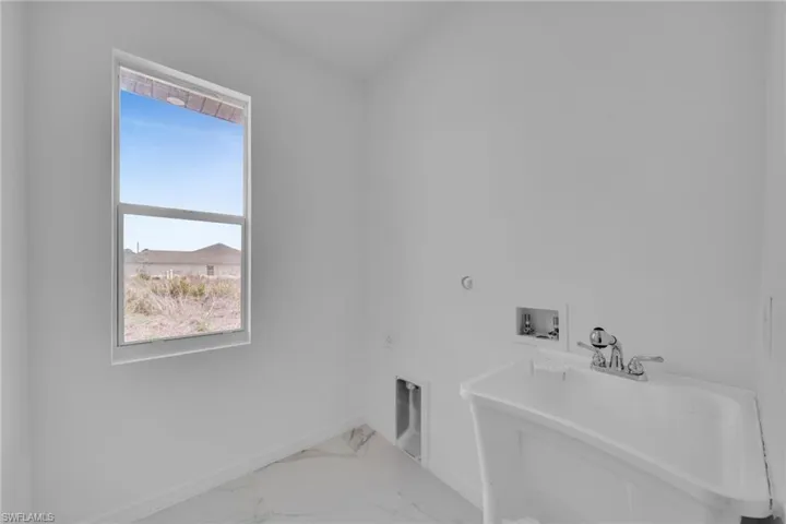 Dedicated utility space featuring a single window, white walls, and white tile flooring