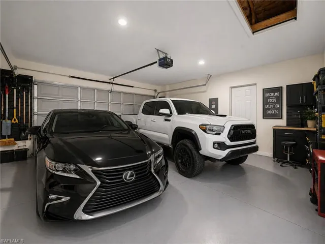 Two-car garage featuring light gray epoxy flooring and overhead lighting