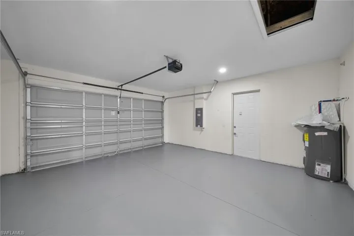 Attached garage featuring a gray floor, white walls, and a white entry door