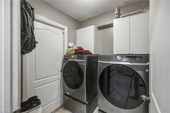 Laundry area featuring white cabinetry, gray wall paint, white trim, and a white interior door