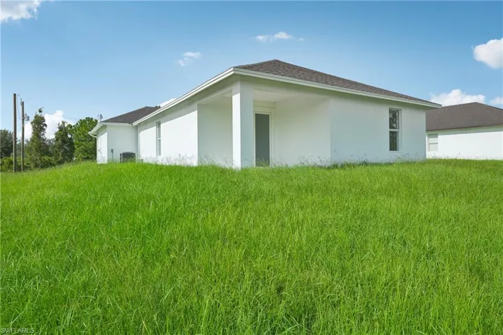 View of side of home featuring cooling unit and a yard