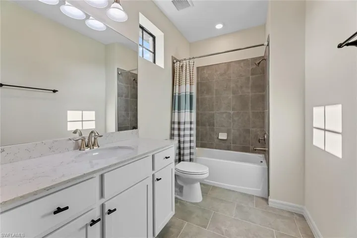 Full bathroom featuring tile flooring, shower / bath combo with shower curtain, toilet, and vanity