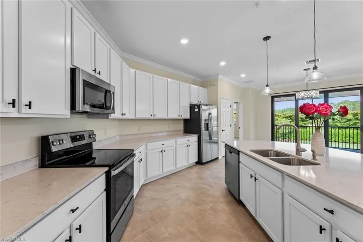 Kitchen with stainless steel appliances, light tile flooring, pendant lighting, sink, and white cabinetry
