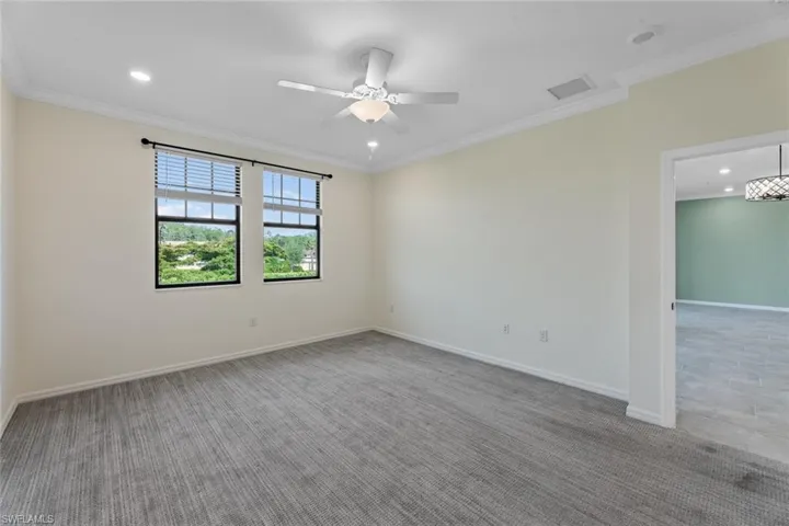 Tiled empty room with ceiling fan and crown molding