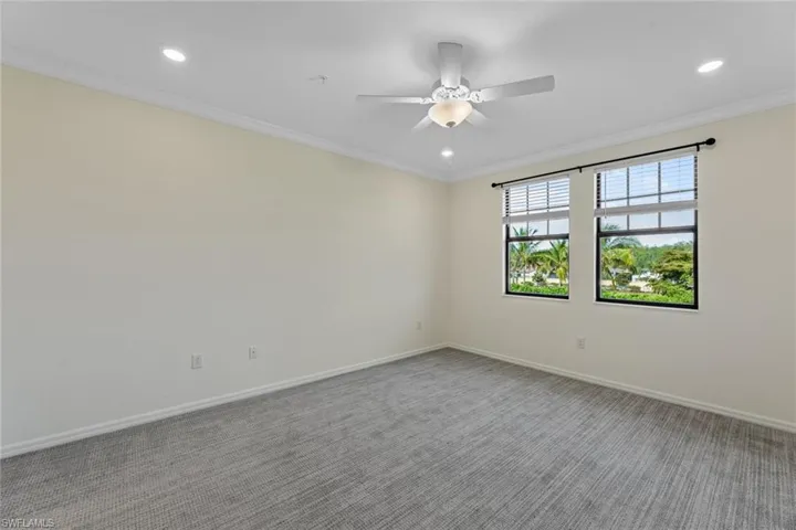 Carpeted spare room with ceiling fan and crown molding