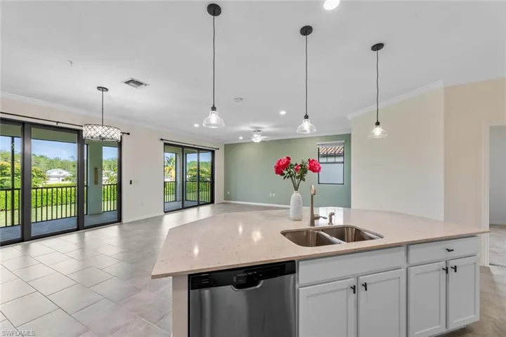 Kitchen featuring sink, light tile flooring, decorative light fixtures, and stainless steel dishwasher