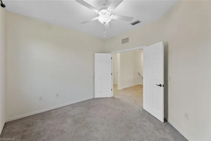 Carpeted empty room featuring ceiling fan