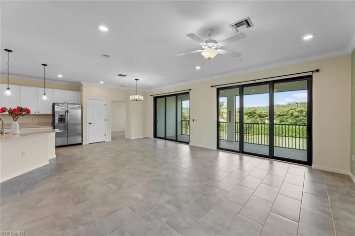 Unfurnished living room featuring plenty of natural light, ceiling fan, ornamental molding, and light tile floors