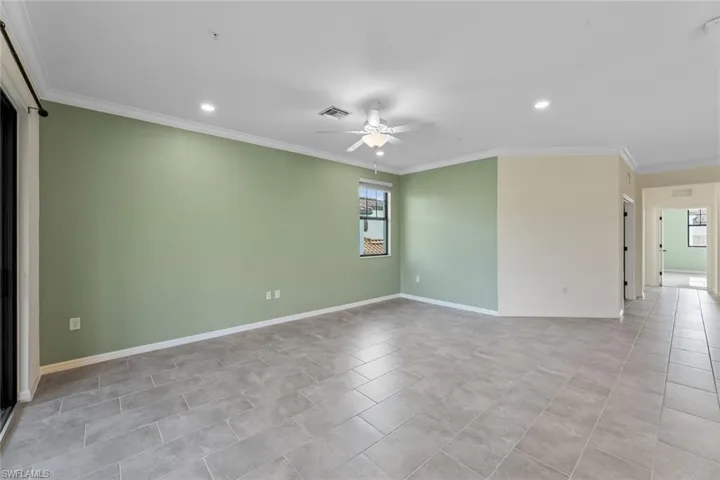 Spare room featuring ceiling fan, light tile floors, and crown molding