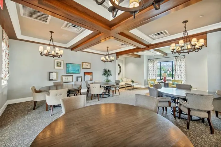 Carpeted dining area with coffered ceiling, beam ceiling, ornamental molding, and a chandelier