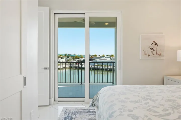 Bedroom featuring a water view, light marble finish flooring, and access to outside - Virtually Edited Image