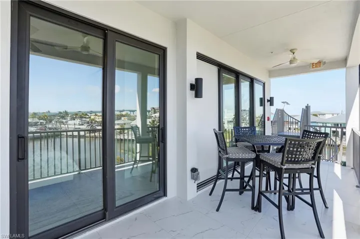 Balcony with a water view, a ceiling fan, and outdoor dining space - Virtually Edited Image