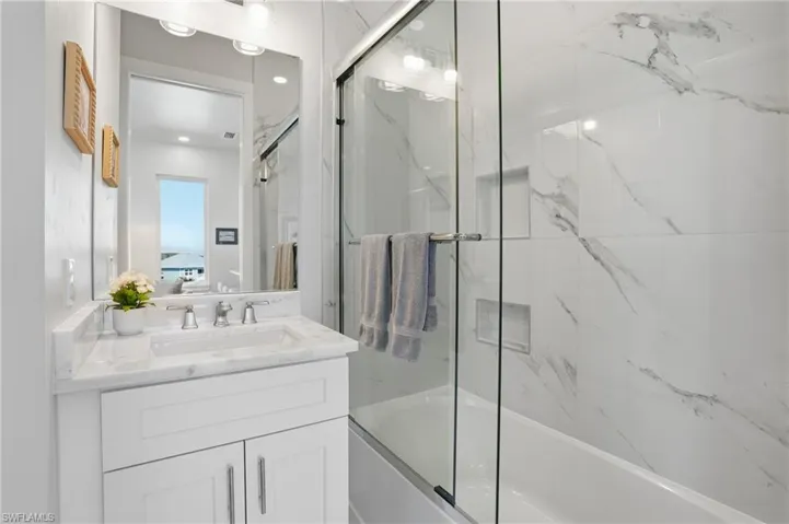 Ensuite bathroom featuring bath / shower combo with glass door and vanity - Virtually Edited Image