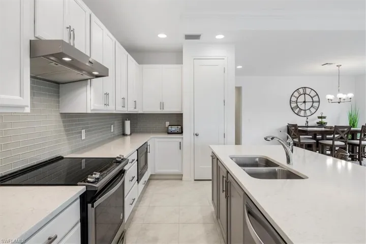 Kitchen featuring a notable chandelier, tasteful backsplash, range with electric stovetop, decorative light fixtures, and sink