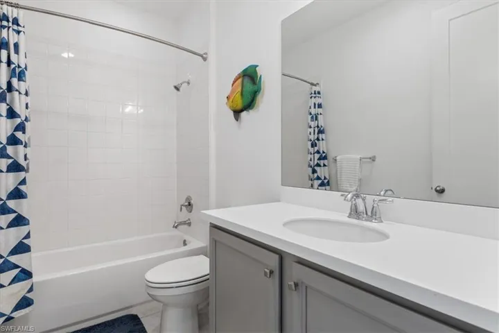 Full bathroom with tile patterned floors, vanity, toilet, and shower / bath combination with curtain
