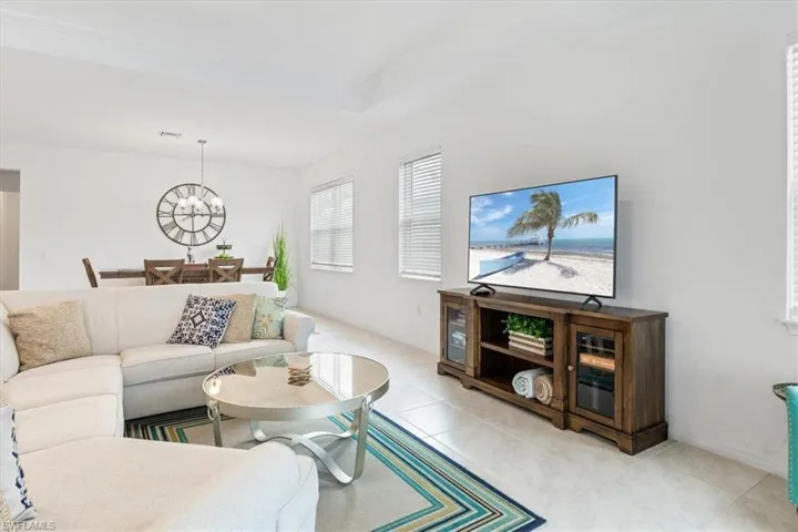 Living room with a raised ceiling, a notable chandelier, and light tile patterned floors