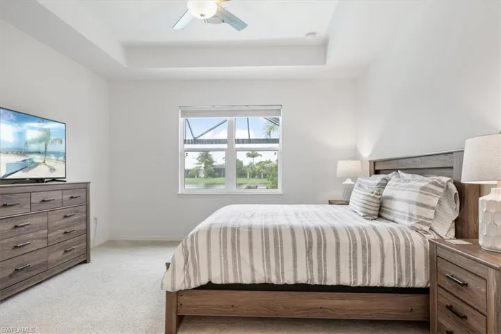 Carpeted bedroom featuring a tray ceiling and ceiling fan