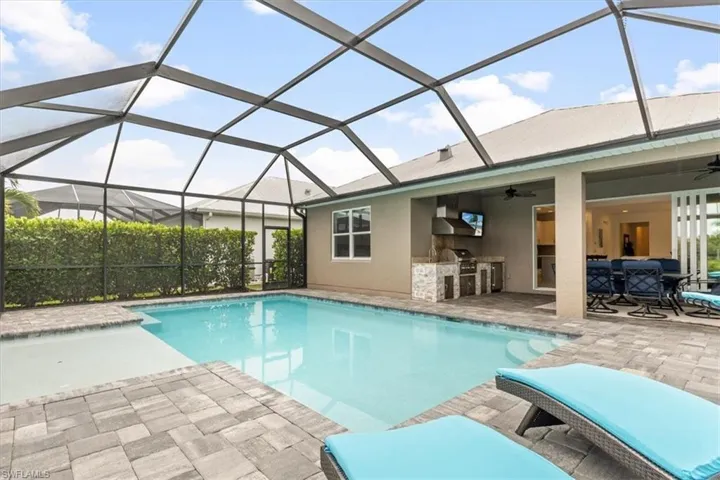 View of pool featuring grilling area, glass enclosure, a patio, and ceiling fan