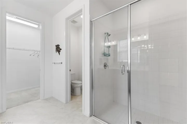 Bathroom featuring a shower with shower door, tile patterned flooring, and toilet