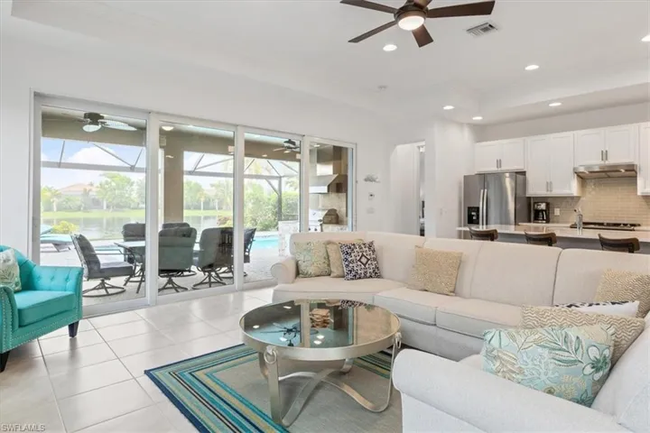 Living room with light tile patterned floors, ceiling fan, and a tray ceiling