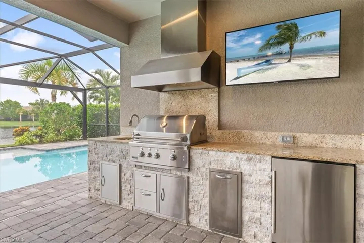 View of patio featuring an outdoor kitchen, grilling area, and glass enclosure
