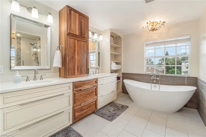 Bathroom featuring vanity, a bathtub, tile patterned flooring, and wainscotting