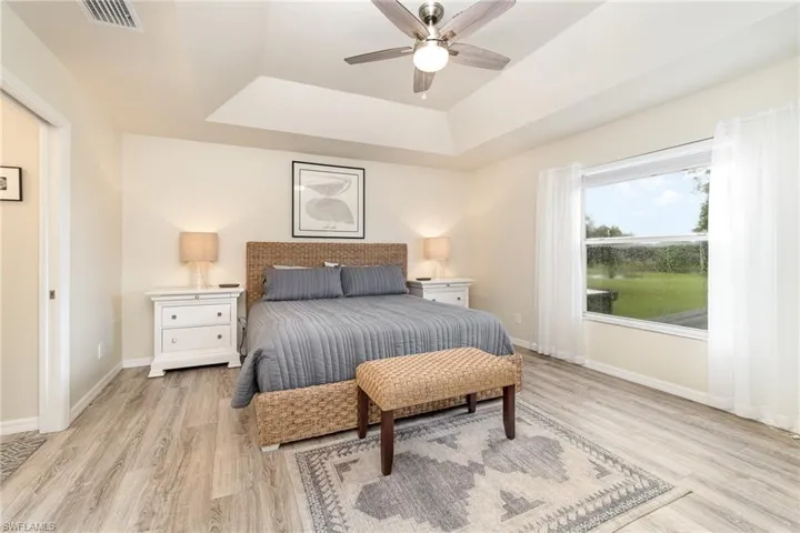 Bedroom with a tray ceiling, ceiling fan, and light hardwood / wood-style flooring