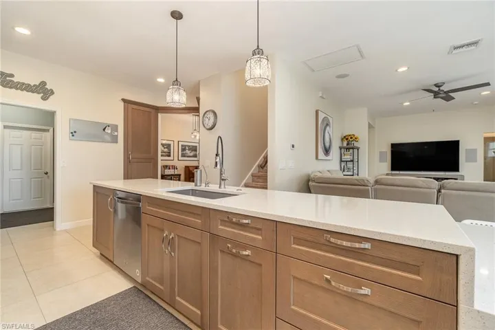 Kitchen featuring light tile patterned flooring, dishwasher, decorative light fixtures, and quartz counters