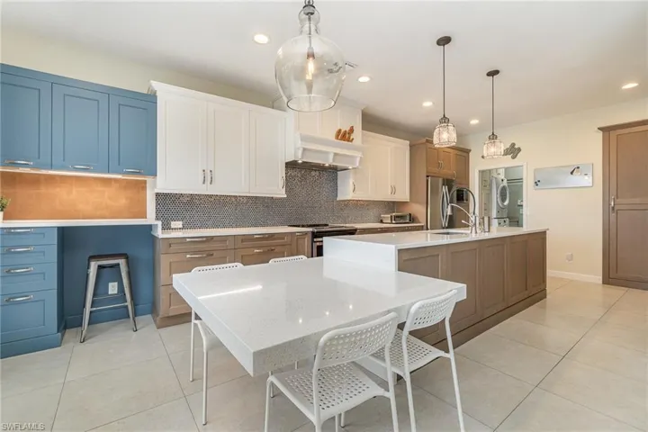 Kitchen featuring a large island, stainless steel appliances, hanging light fixtures, and ventilation hood
