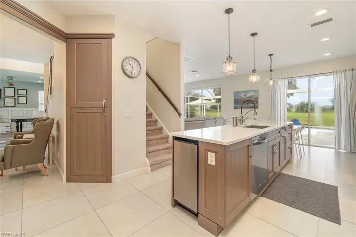 Kitchen with light tile patterned flooring, hanging light fixtures, a center island with sink, and appliances with stainless steel finishes
