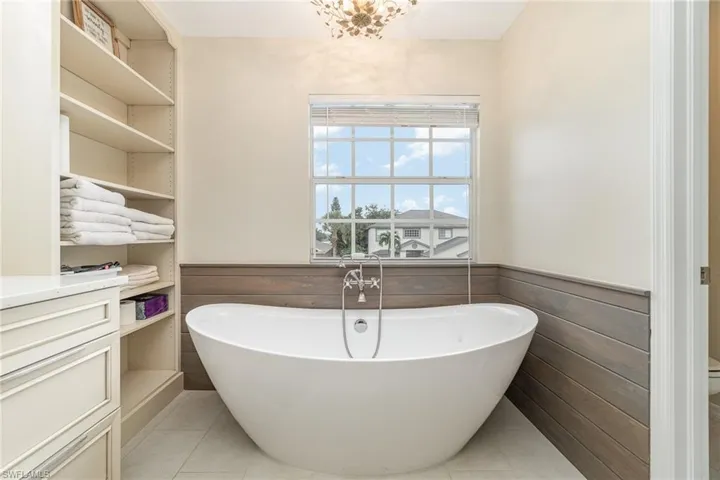 Bathroom featuring tile patterned flooring, wainscotting, tub, and vanity