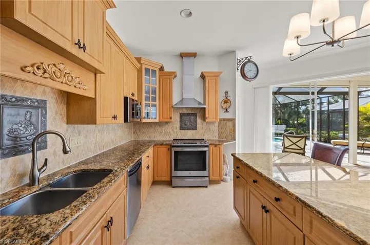 Kitchen featuring tasteful backsplash, appliances with stainless steel finishes, a sunroom, dark stone countertops, and wall chimney range hood