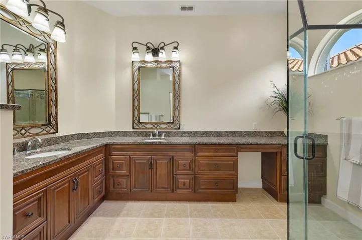 Bathroom with double vanity, a stall shower, and light tile patterned floors